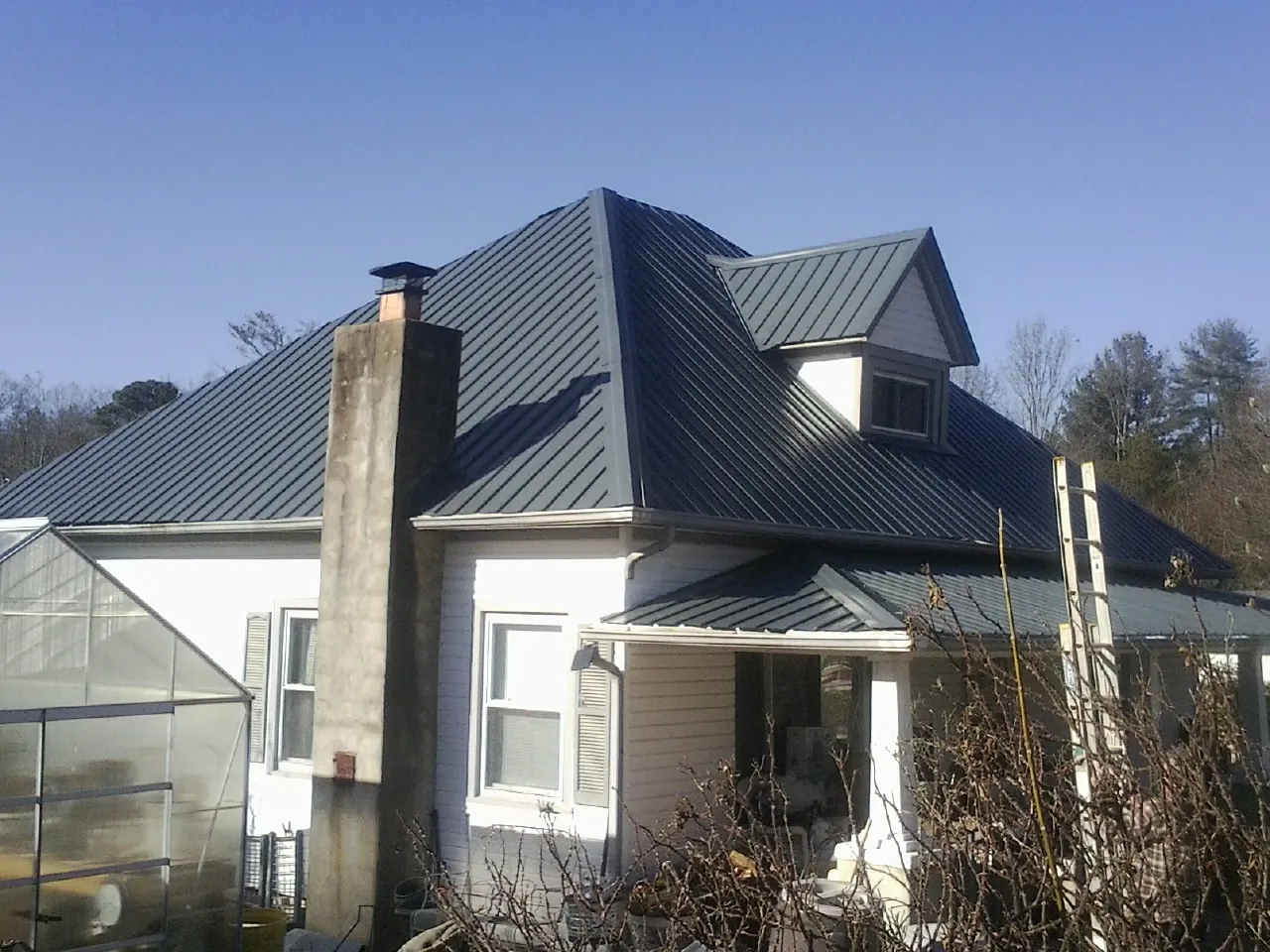 Dark blue standing seam metal roof on a white farmhouse with dormer — Slate & Tile Roof Repair by Roofing Brothers in Kalamazoo