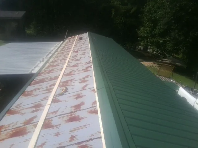 Old rusted panels beside newly installed green metal roofing — Wind Damage Roof Repair by Roofing Brothers in Kalamazoo