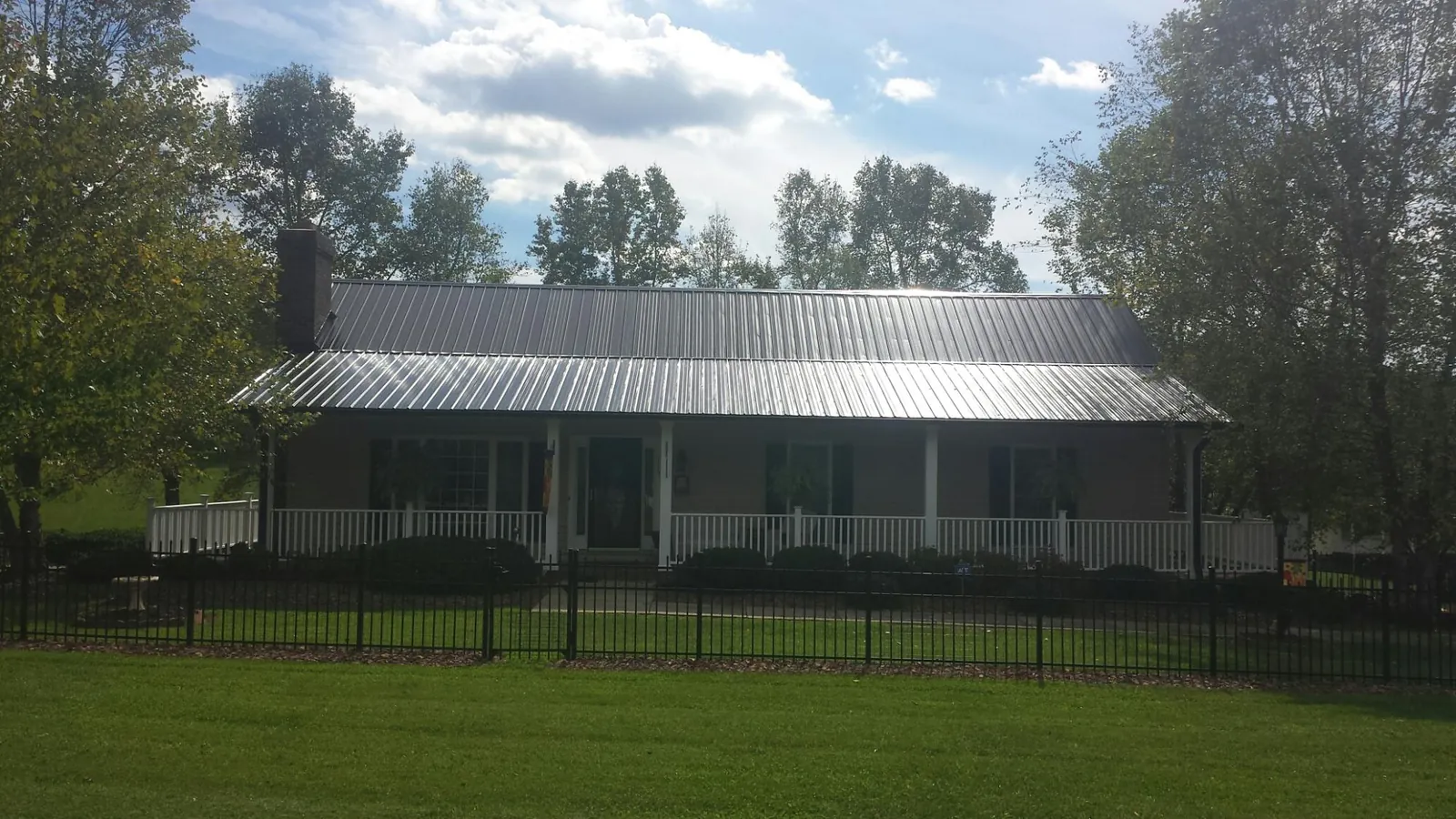 Gray metal roof on a brick ranch with a full width front porch — Gutter Guard Installation work by our crew in Kalamazoo