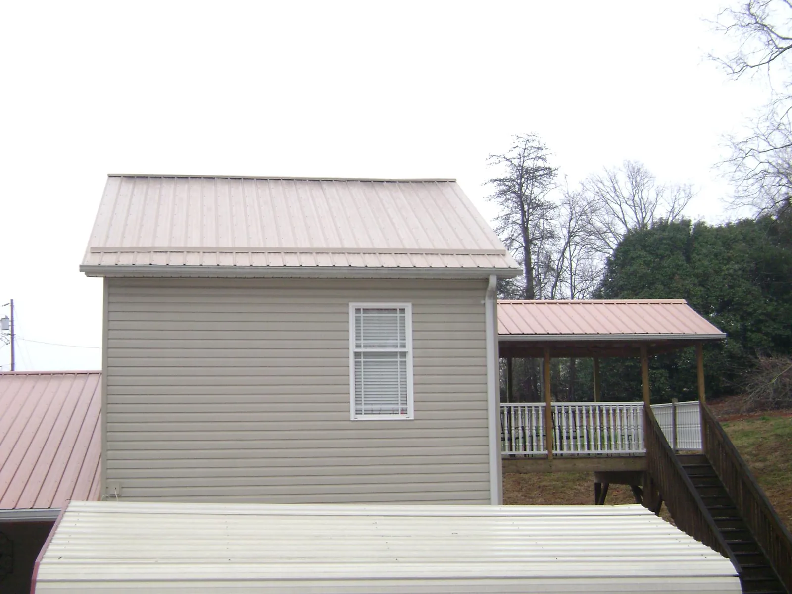 Tan metal roofs on a two story addition and attached porch, from a Roof Replacement job in Kalamazoo