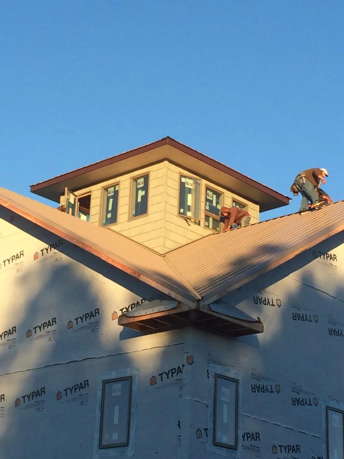 Roofers working around a rooftop cupola on a new metal roof at sunset — Roof Waterproofing in Kalamazoo by Roofing Brothers